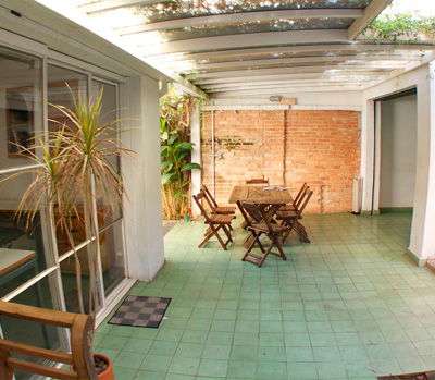 Área externa com jardim, mesa de madeira e plantas